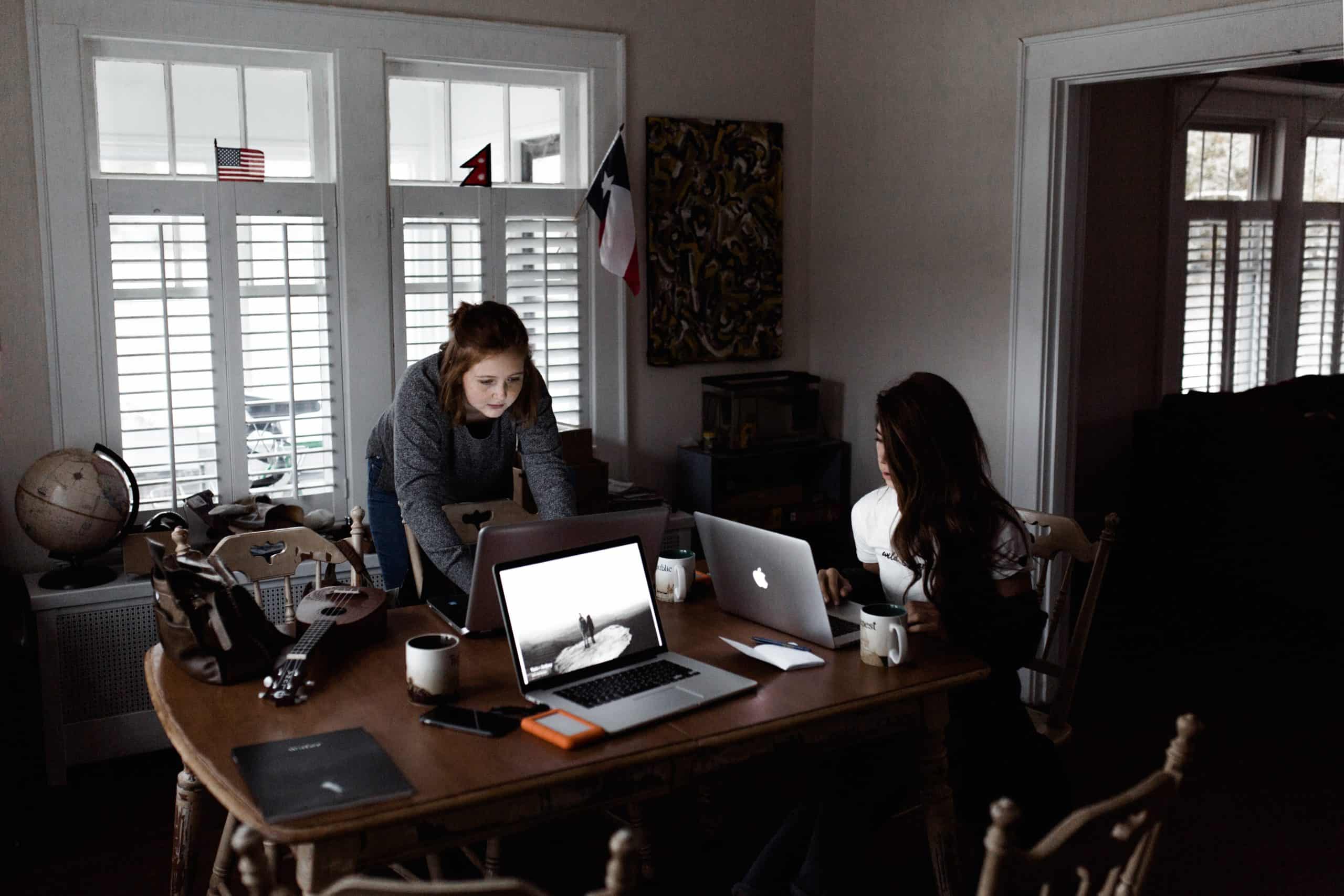 Andrew Neel Unsplash image two women online learning laptops on long table