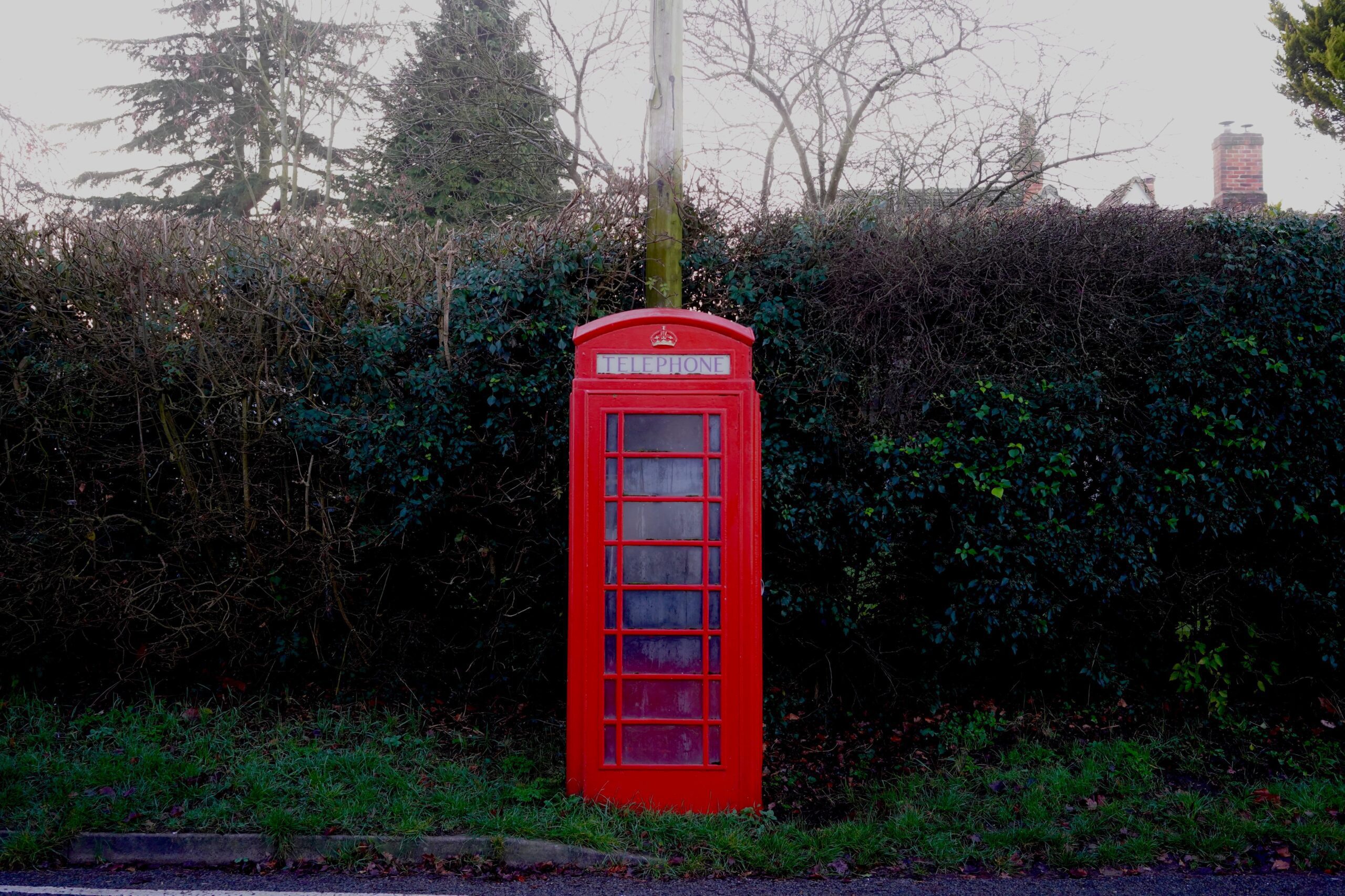 jack-bassingthwaighte-UK red phone box at pole backed up by hedgrow-unsplash