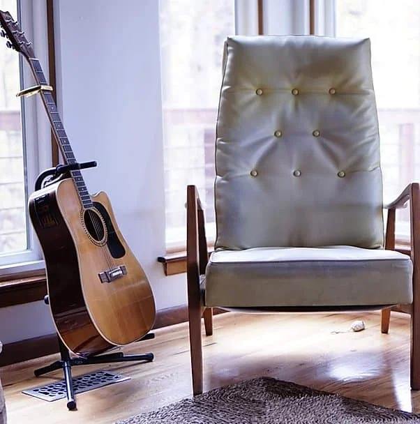 Home Comfort stay interior with mid century modern chair and acoustic guitar on stand