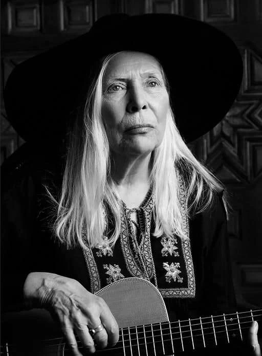 Joni Mitchell with black sombrero and guitar
