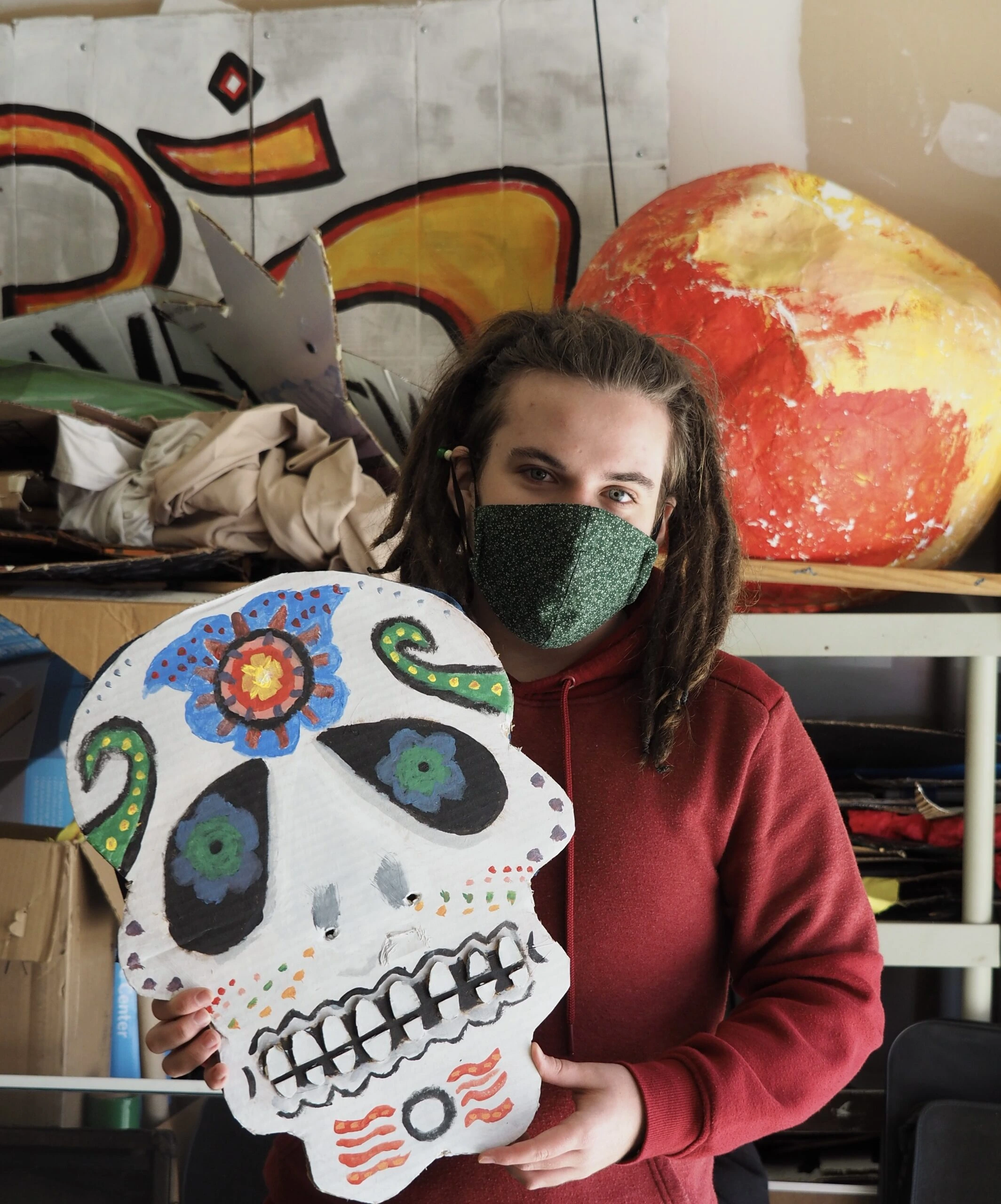 Sol Ramirez with Covid Mask holding skeleton Head mask in workshop by Aeon Schmoock