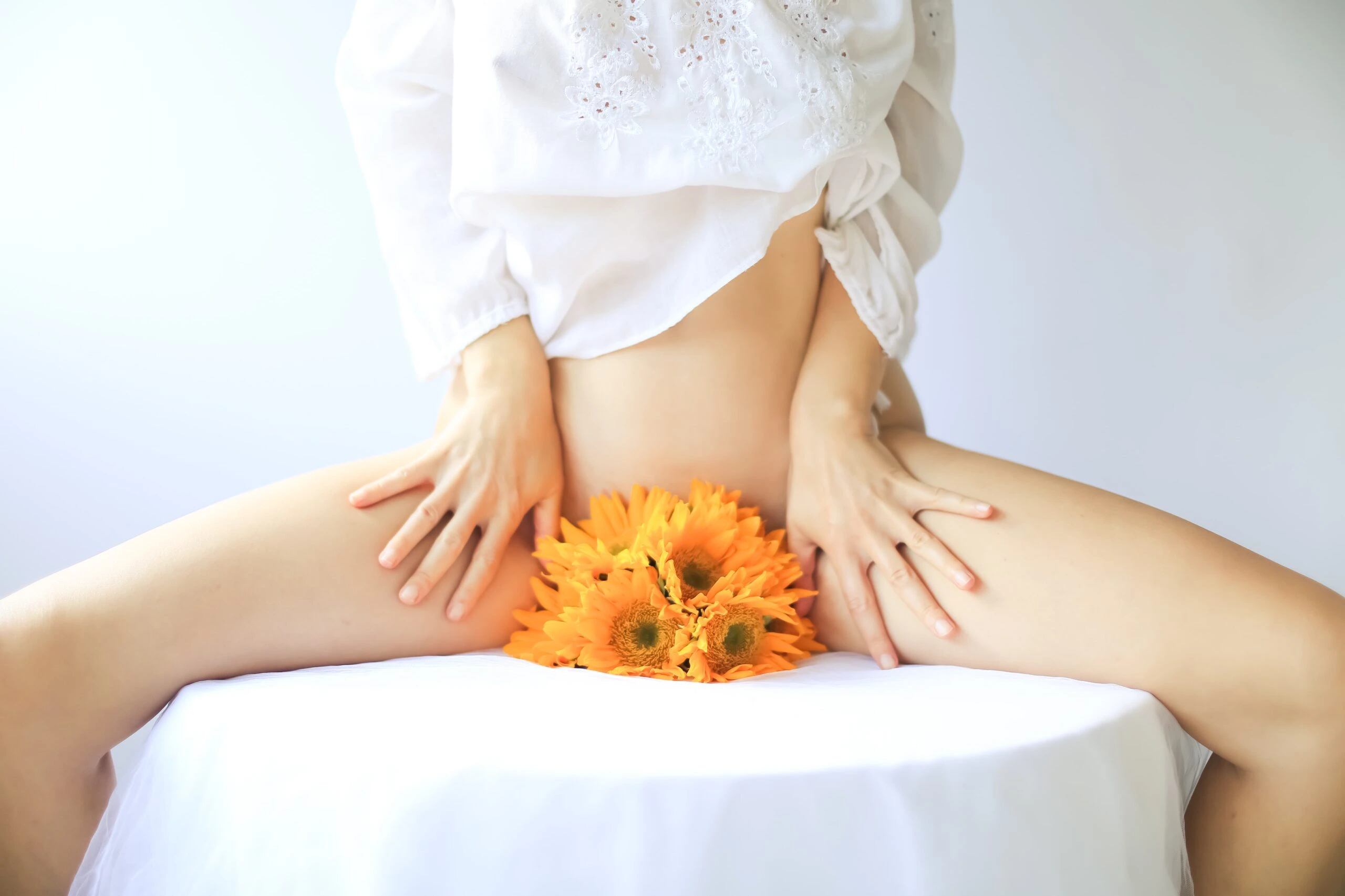 ava-sol-Woman with orange daisy blossoms held between legs -unsplash