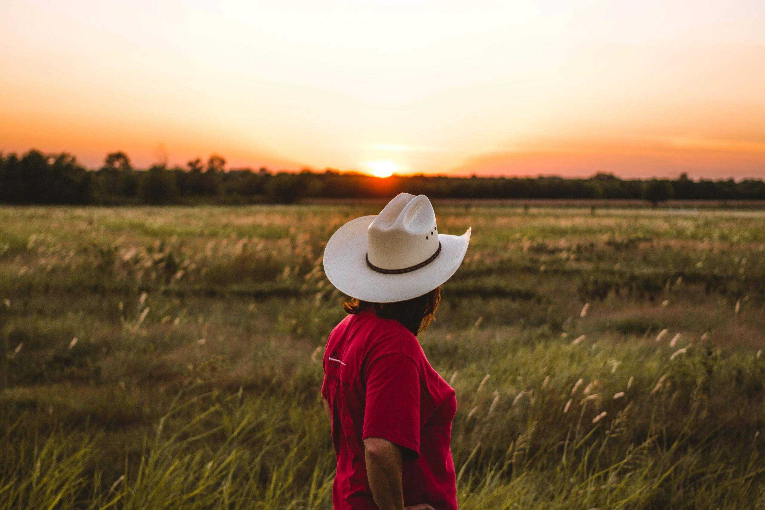 justin-clark-cowgirl looking out over prarie sunset-unsplash
