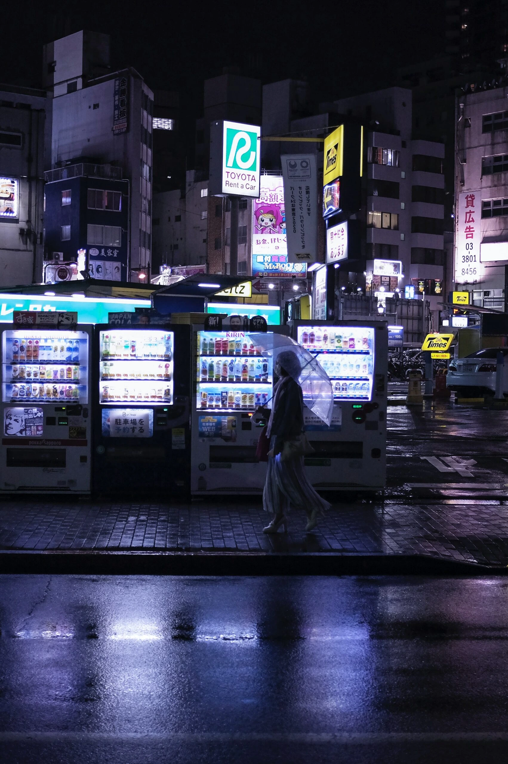hakan-nural-Tokyo City Scene rainy night with woman walking by s row of vending machines-unsplash