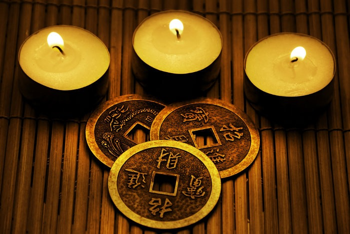 Three votive candles and 3 Chinese bronze divination coins on bamboo mat