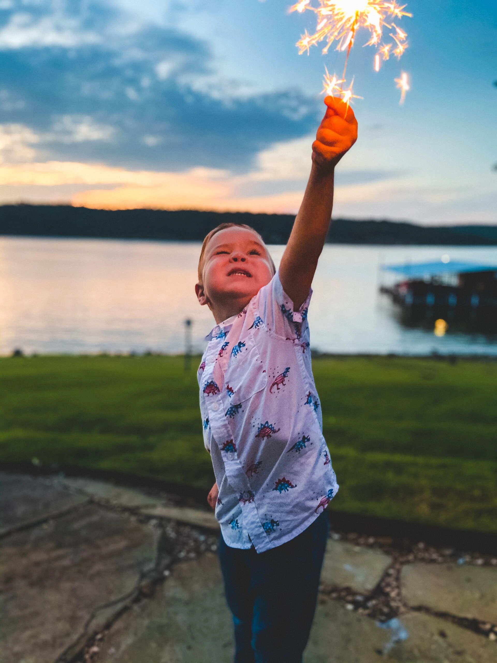 bobby-overturf-Young man holding high a lit sparkler on 4th of July-unsplash