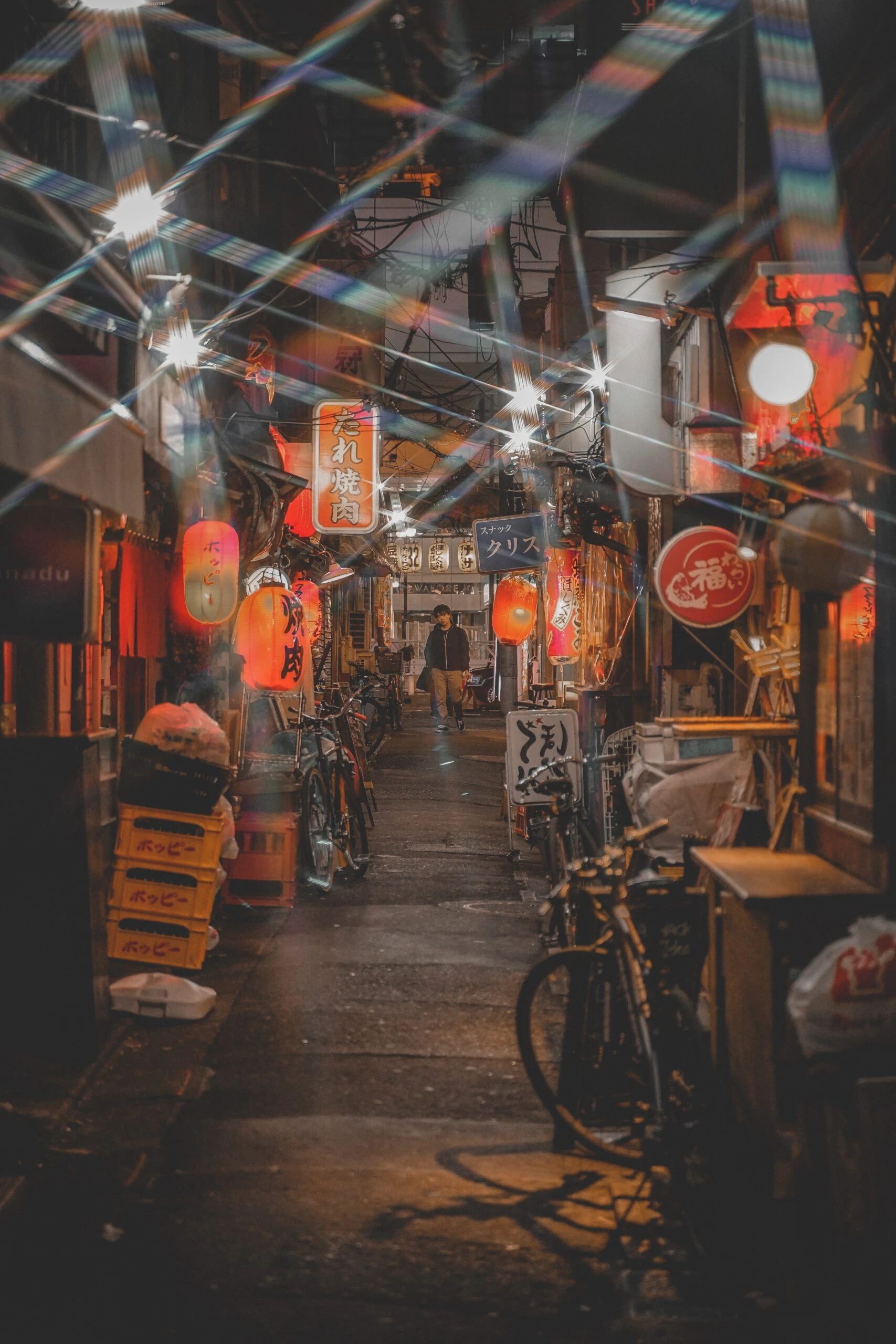 yoav-aziz-pedestrians walking through a lantern lit alleyway with shops and merchants either side-unsplash