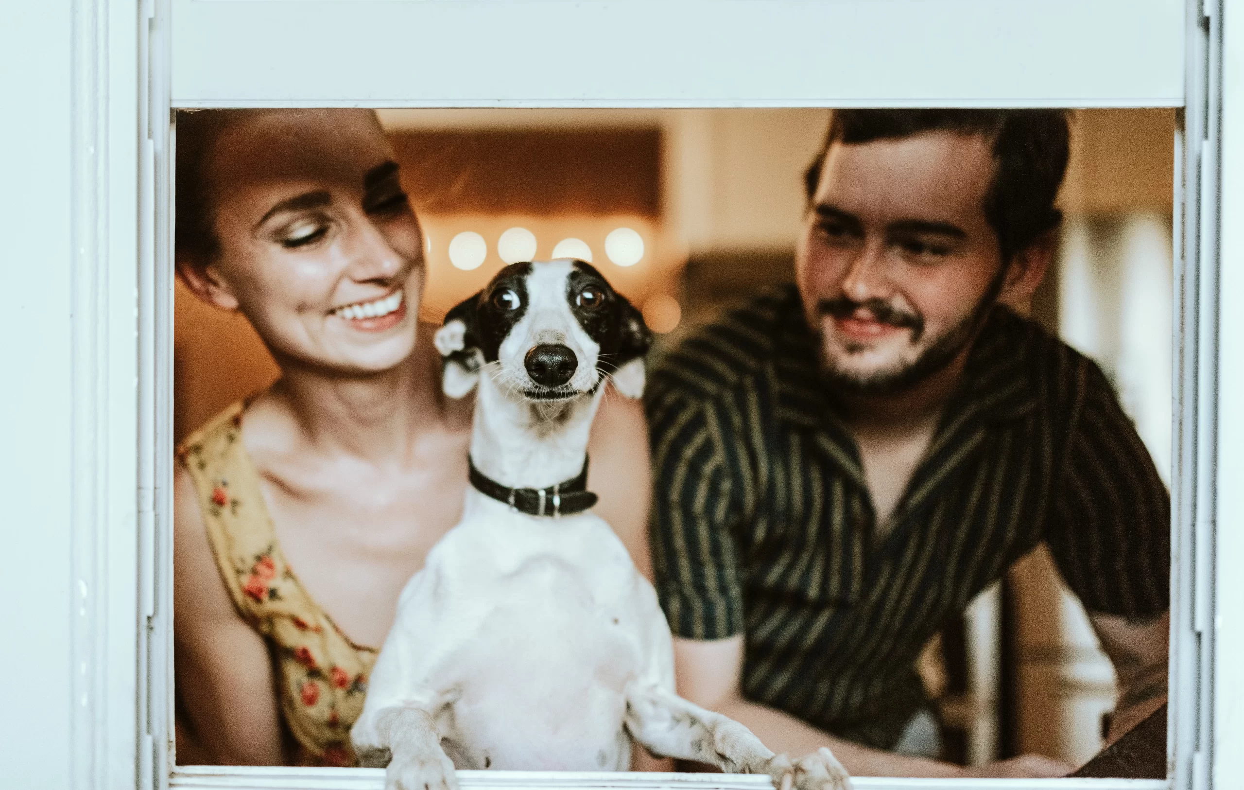 chewy-dog with long snout stnds between couple with comedy_4Q-unsplash